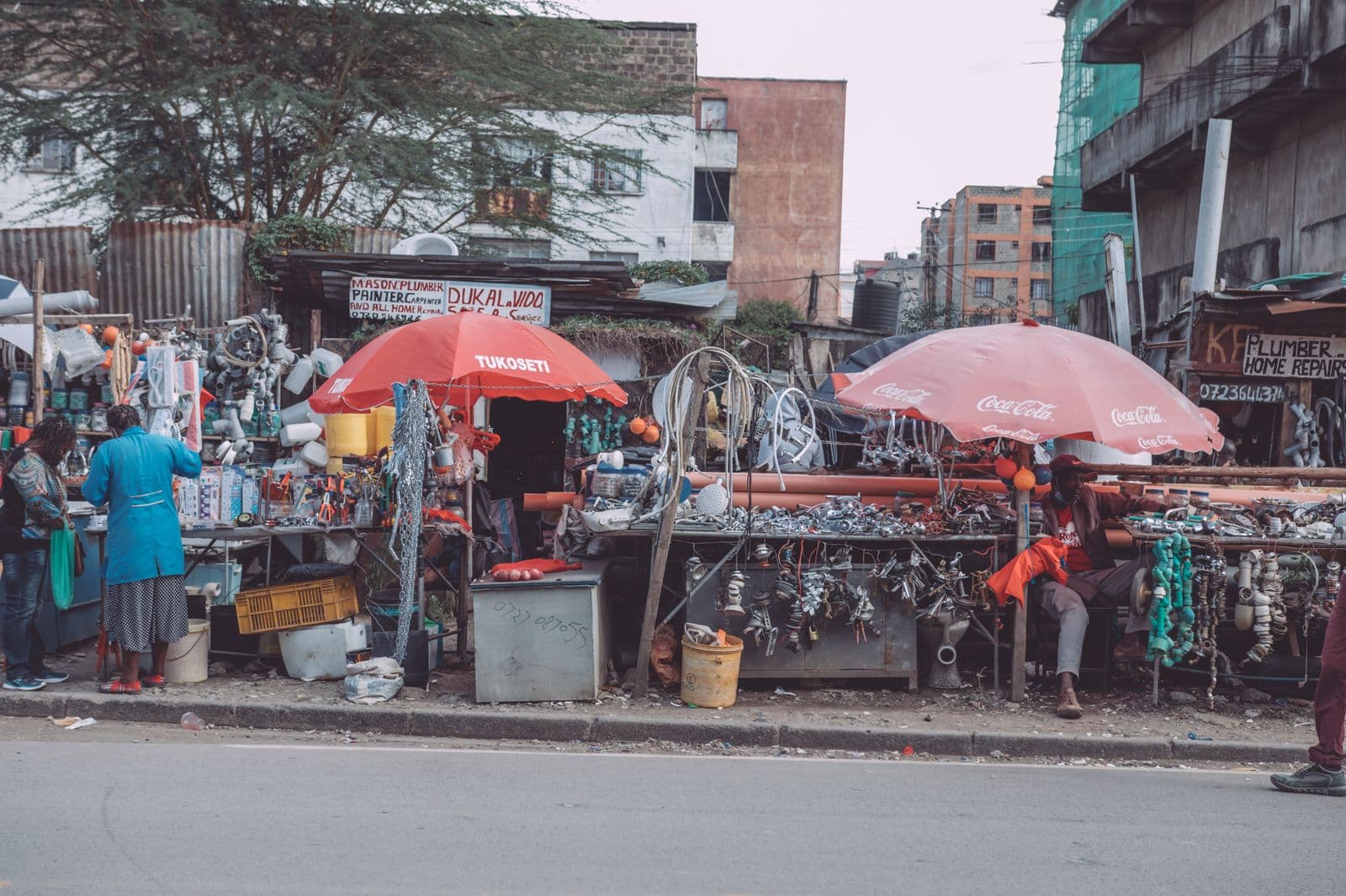 A busy street market in Nairobi with vendors selling goods under umbrellas, the kind of weekend hustle many employed Kenyans run on the side