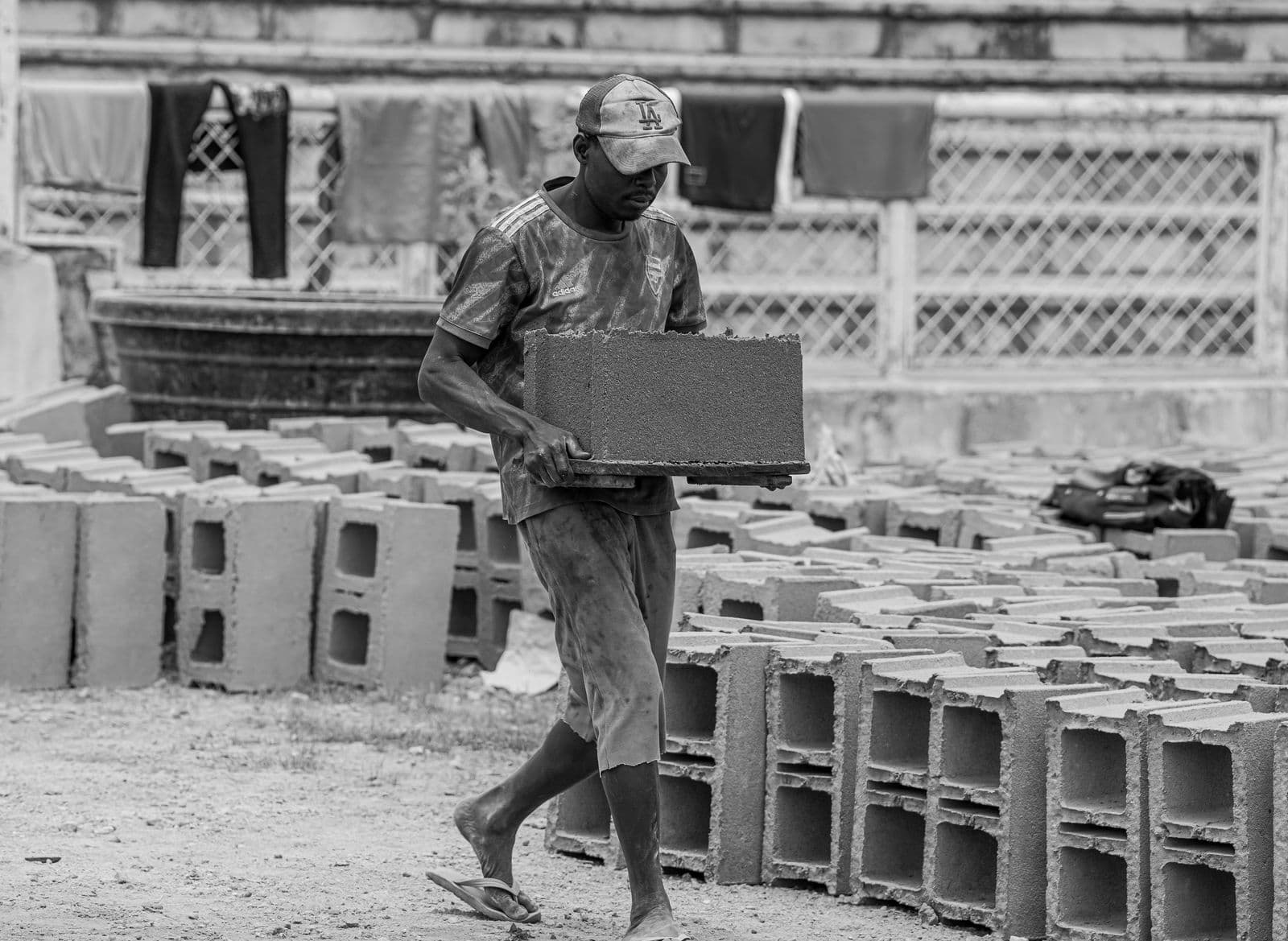 A construction worker carrying a concrete block at a building site in Africa, the kind of labour cost that adds up when building a 3-bedroom house
