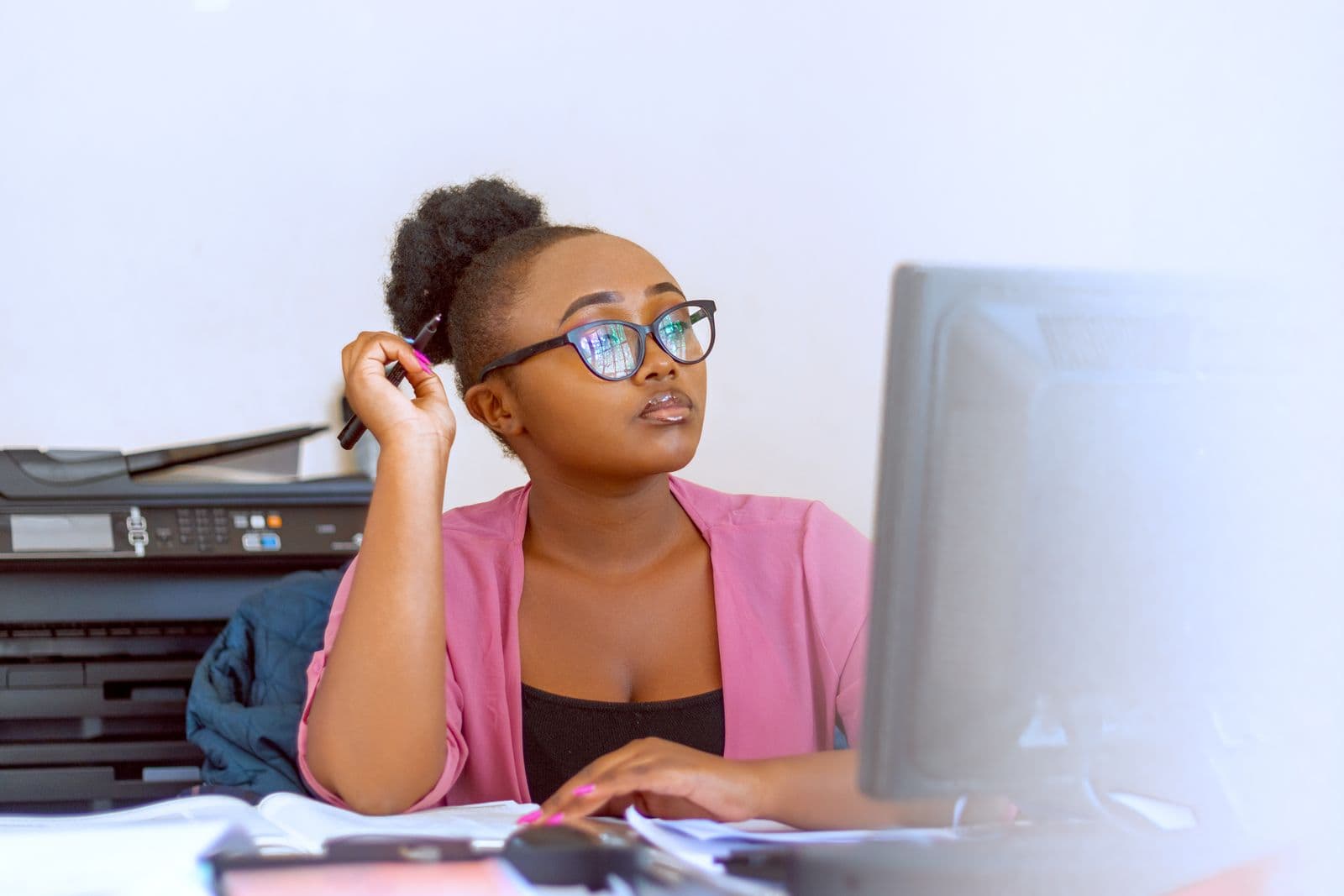 A Kenyan small business owner checking paperwork and her computer at her office desk.