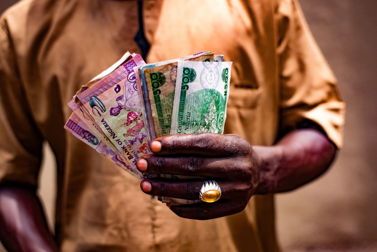 A man holding Nigerian naira banknotes outdoors in Bida, Nigeria