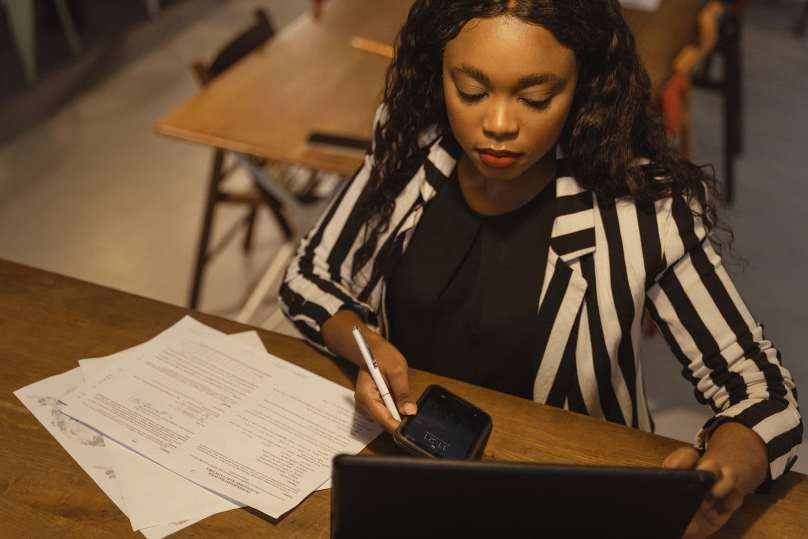 A woman reviewing paperwork and a laptop at a desk while filing her tax return online