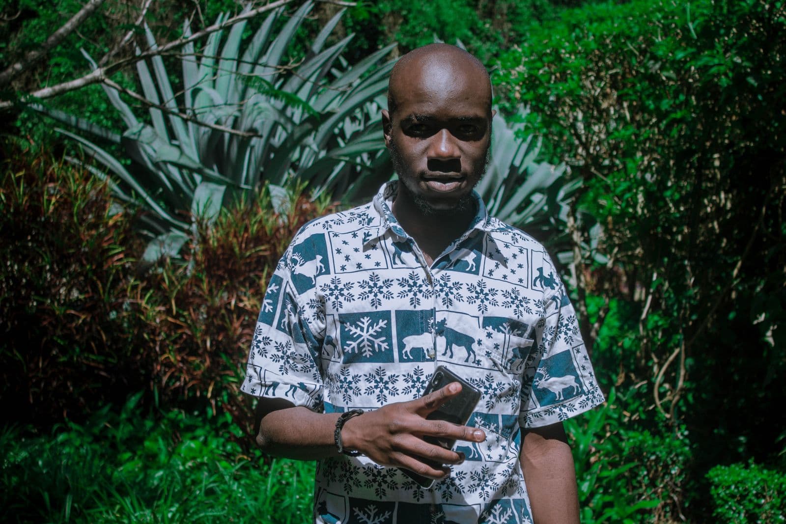 A man holding a smartphone in a garden in Machakos, Kenya