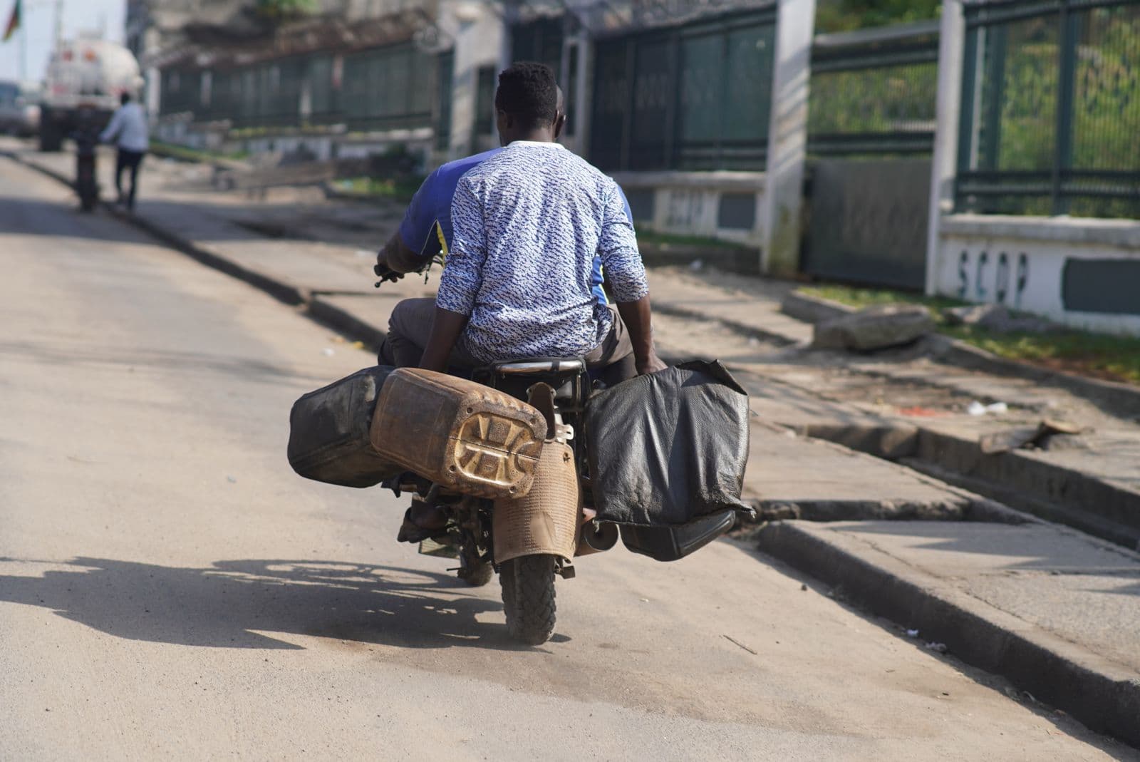 Man riding a motorbike loaded with goods on a sunny street in Douala, Cameroon
