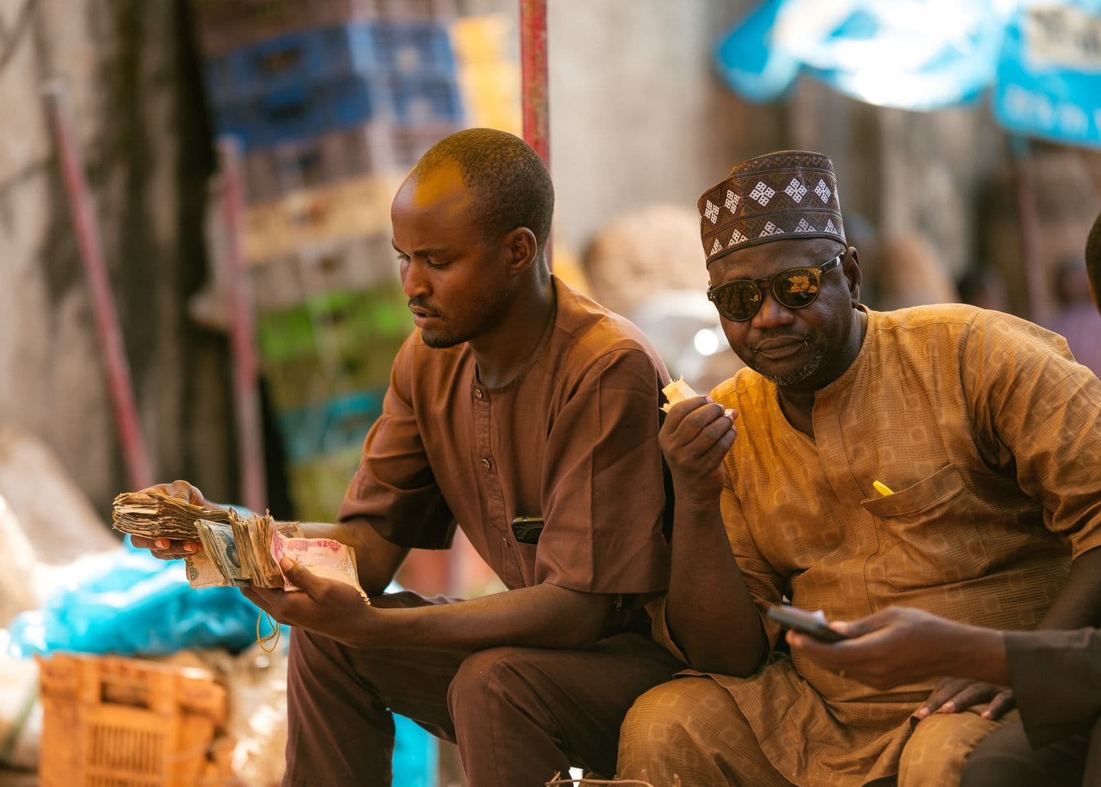 Men counting naira notes at a market in Tudun Wada, Nigeria
