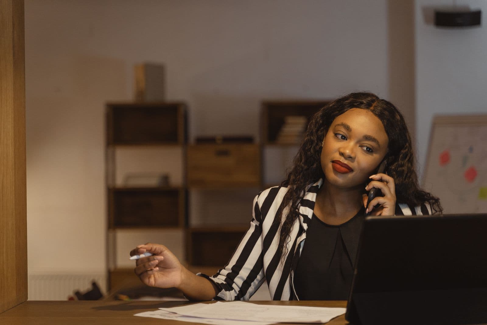 Office worker at her desk on a phone call, reviewing payroll