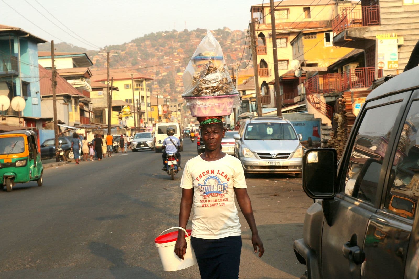 Street vendor carrying goods on her head on a busy street in Freetown, Sierra Leone