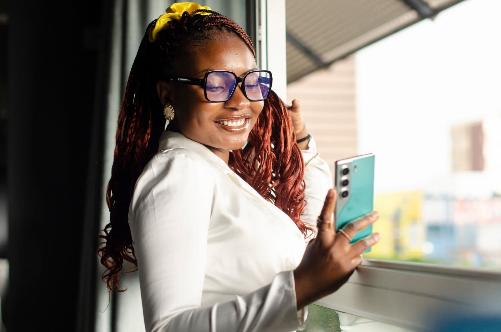 Woman in Lusaka checking Airtel Money charges on her smartphone by a window