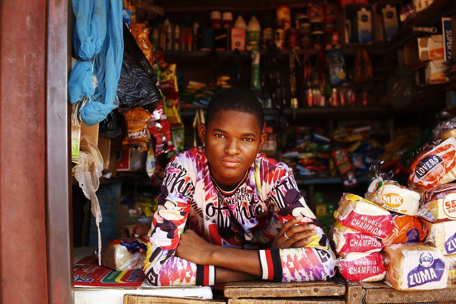 Young Nigerian man leaning on a market stall counter in Abuja, Nigeria